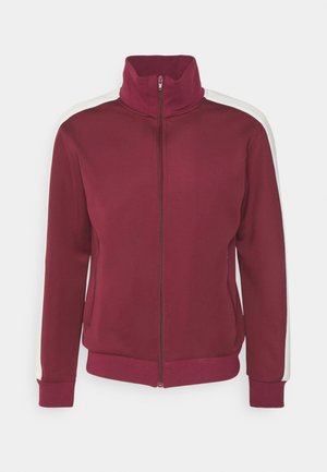 Bordo zip-up jakna z visokim ovratnikom, belimi ramenskimi črtami in žepki s rebrastimi manšetami. Mehka tkanina in eleganten dizajn za udobno nošnjo.