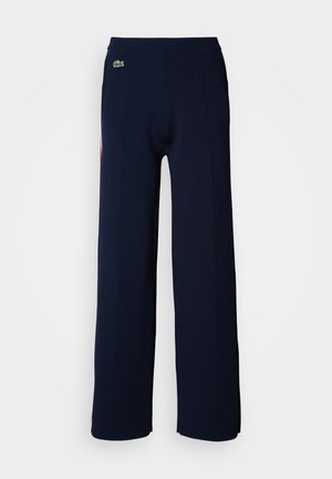 Navy blue wide-leg pants with a soft texture, featuring a ribbed waistband and a small green logo on the front, highlighting a clean design.