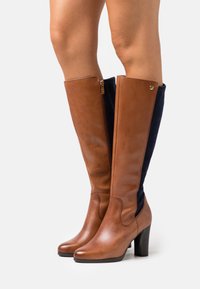 Brown leather knee-high boots with navy suede panels, zipper closure, and a rounded toe. Stacked heel adds height and stability.