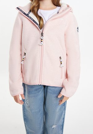 Barn iført lyserød hættejakke med lynlås og hvidt fleecefor og blå jeans med sommerfugl-patch på venstre lår.