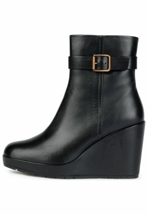 Bottine compensée en cuir noir à texture lisse, hauteur mi-mollet, avec une sangle décorative munie d'une boucle en laiton.