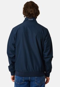 M�ørkeblå, letvægtsjakke med ståkrave, elastisk talje og "SEASIDE" broderi på ryggen. Glat tekstur og afslappet design.