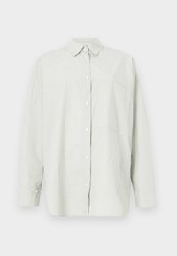 Chemise gris clair à manches longues, boutonnée, avec col et une poche poitrine, présentée sur un fond uni.