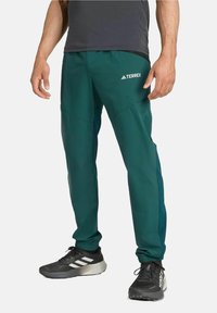 Pantalons de sport verts en matériau léger, dotés de poches latérales, de poignets côtelés et du logo TERREX sur la cuisse.