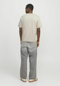 Lys beige bomull t-skjorte med rund hals, korte ermer og en avslappet passform, kombinert med høyt liv, lysegrå jeans.