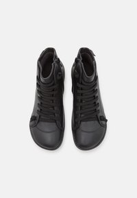 Scarpe nere alta in pelle e tessuto, caratterizzate da una combinazione di lacci e cerniere, con una texture liscia e un design della punta arrotondata.
