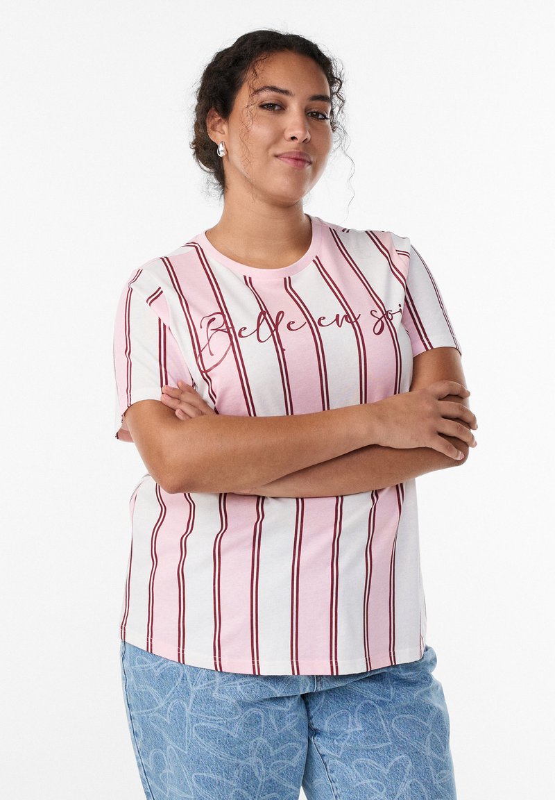 Light pink t-shirt with vertical maroon stripes and text "Belle en soi." Short sleeves, round neckline, paired with light blue patterned jeans.