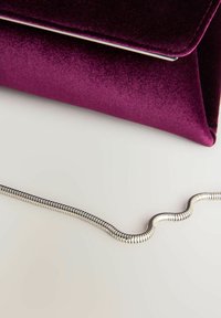 Pochette en velours violet avec une bandoulière chaîne métallisée argentée ; présente un design élégant et structuré ainsi qu'une texture lisse. Aucun détail de quincaillerie visible.