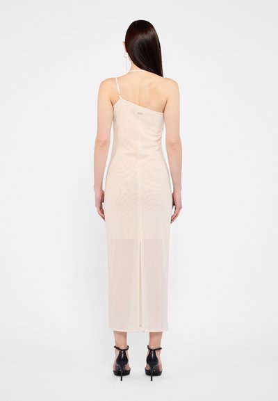 Light peach, sheer midi dress with one adjustable strap, a straight cut, and a slit at the back. Worn with black heeled sandals.