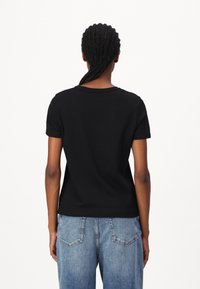 Zwart t-shirt met korte mouwen en een ronde hals, gemaakt van katoen. Gecombineerd met lichtblauwe, relaxed-fit denim jeans met achterzakken.