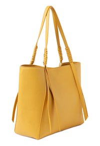 Bolso tote de cuero amarillo con asas trenzadas y borlas laterales. Diseño abierto, forma estructurada, textura suave y sin hardware visible.