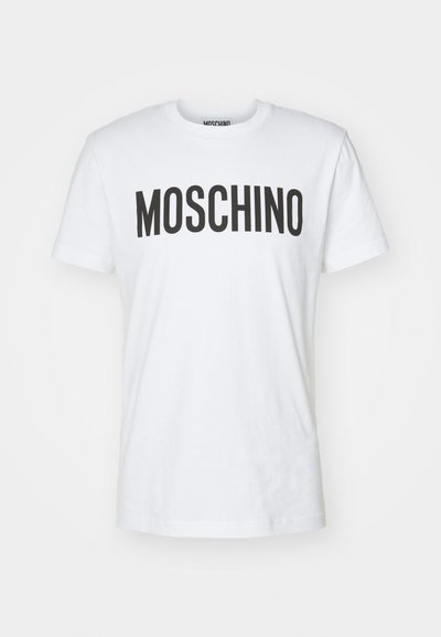 Camiseta de algodón blanca con llamativas letras negras "MOSCHINO" en la parte frontal. Manga corta y cuello redondo. Textura suave.