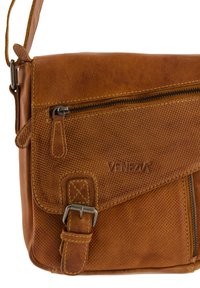 Brązowa skórzana torba na ramię z teksturowanymi akcentami, z przednią kieszenią na zamek i regulowanym paskiem. Posiada wytłoczone logo "VENEZIA."