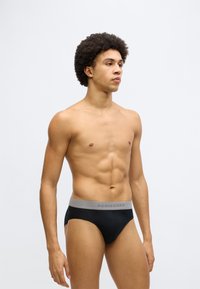 Fekete férfi alsónadrágok puha, elasztikus szürke derékpánttal, amelyen a "SCHIESSER" márkajelzés látható. Sima anyag és testhezálló szabás, a kényelem érdekében tervezve.