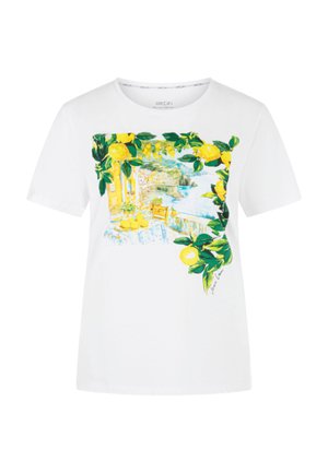White t-shirt with a colorful print of lemons, green leaves, a table with lemons, and a coastal village scene.