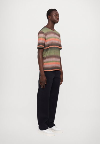Short-sleeve, ribbed knit shirt in green, orange, and brown stripes, paired with dark pants and white sneakers. Smooth texture with contrasting sleeves.
