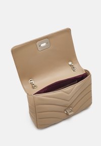 Beige gesteppte Lederhandtasche mit einem goldenen Verschluss, ausgestattet mit einem gefütterten Innenraum in tiefem Burgunderrot und Kettenakzenten an den Seiten.