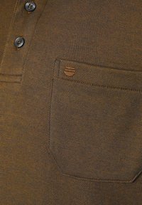 Braun meliertes Poloshirt mit einer Drei-Knopf-Leiste, einer Brusttasche mit besticktem Akzent und kontrastierenden Nähten.