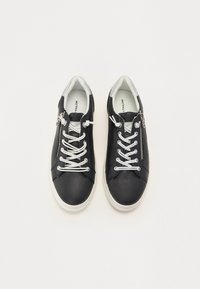 Baskets en cuir noir avec des lacets blancs et une fermeture éclair sur le côté. Elles possèdent un intérieur doux et des accents gris au niveau du talon. Design à bout arrondi.