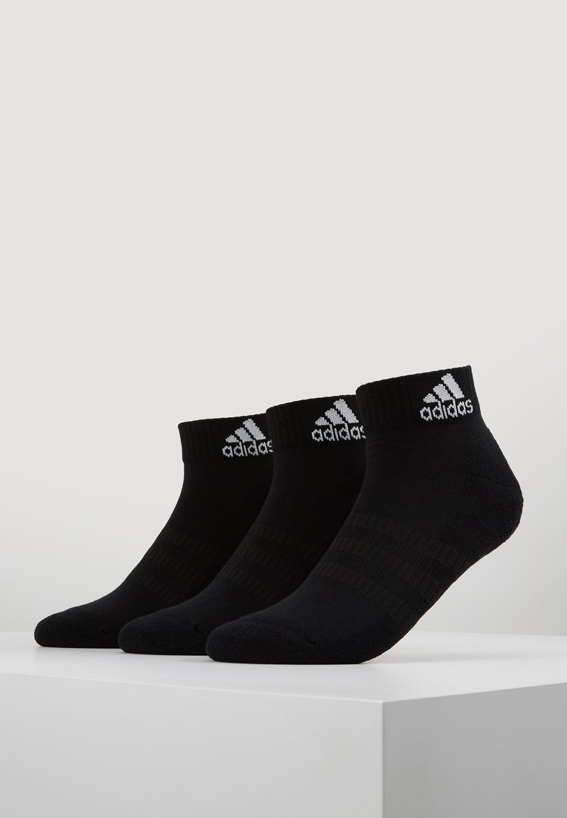 Tres pares de calcetines deportivos negros con puños acanalados y tres franjas horizontales. Presenta el logo de Adidas en blanco en el puño. Material de mezcla de algodón.