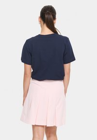Navy blue t-shirt with short sleeves, paired with a light pink pleated skirt. The outfit features a simple design with clean lines.