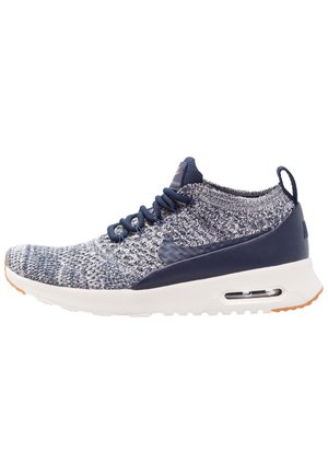 Strickstoff-Sneaker in Marineblau und Weiß, ausgestattet mit einem gepolsterten Schaft, blauen Schnürsenkeln, Luftpolsterung und einer strukturierten Sohle mit einem Gummi-Akzent.