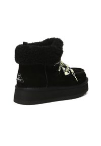 Black ankle boot with thick fleece cuff, patterned laces, thick sole, and brand logo patch on heel side.
