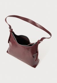 Borsa a tracolla in pelle borgogna con una texture liscia, zip argentata e tracolla regolabile, con una sezione aperta.