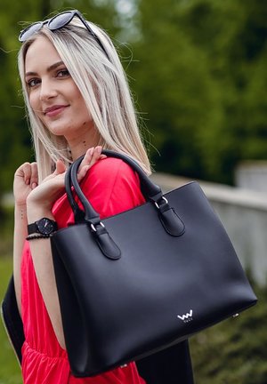 Black leather handbag with structured design, dual top handles, and metal hardware. Features a logo at the bottom and a smooth texture.