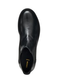 Chaussure en cuir noir avec une finition lisse, bout arrondi, panneaux latéraux élastiques et un logo de marque jaune. Design minimaliste sans embellissements.
