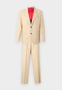 Beige jakkesæt bestående af en skræddersyet blazer og matchende bukser. Blazeren har sorte knapper og rød inderside. Glat stofstruktur.
