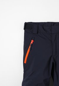 Marineblauwe outdoor broek met een verstelbare tailleband, voorzien van een oranje ritszak aan de zijkant en zacht, textuurstof.