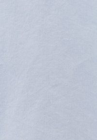Tissu bleu clair avec une texture douce et lisse. Le tissage est légèrement irrégulier, ajoutant de la profondeur à l'apparence générale. Aucun motif visible.