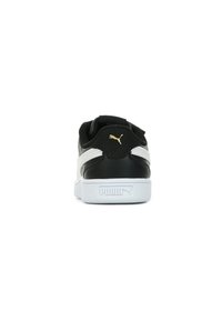 Sneakers Puma in bianco e nero con tomaia in pelle liscia, forma arrotondata, pannelli laterali testurizzati e un accento del logo dorato sul tallone.