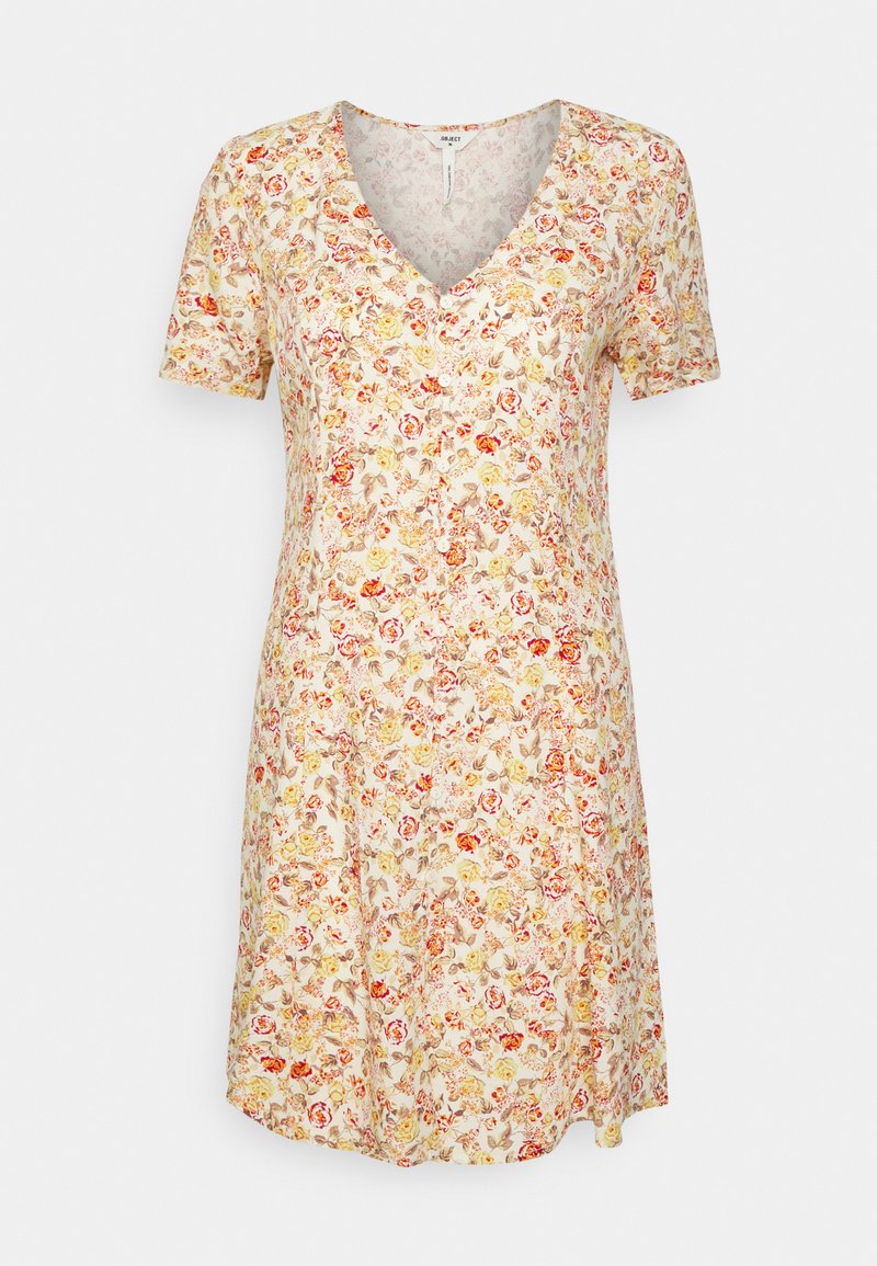 Vestido floral em creme com mangas curtas, decote em V e saia ampla. Apresenta padrões de flores vermelhas, amarelas e verdes. Tecido leve.