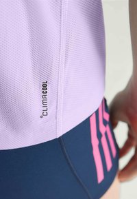 Svijetloplav majica za sport s mrežastim materijalom i "CLIMACOOL" oznakom; u kombinaciji s tamnoplave kratke hlače s ružičastim prugama.