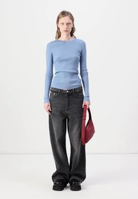 Light blue ribbed long-sleeve top, oversized dark gray jeans, chunky black platform shoes, and a small red handbag with a strap.