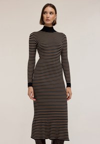 Sukienka z prążkowanego materiału w poziome paski, z długimi rękawami, wysokim dekoltem i rozszerzanym dołem. Kolory to czarne i beżowe paski.