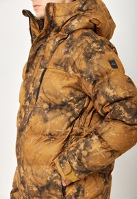 Braun- und schwarz gemusterte Steppjacke mit Kapuze, ausgestattet mit einem Reißverschluss vorne, gesticktem Logo und elastischen Bündchen für einen snug fit.