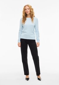 Ανοιχτό μπλε πλεκτό πουλόβερ με στρογγυλή λαιμόκοψη, συνδυασμένο με μαύρο παντελόνι κανονικής γραμμής και μαύρες γόβες με μυτερή μύτη.