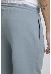 Pantalons de jogging bleu clair en tissu doux, dotés d'une taille élastique, de poches latérales et d'une texture subtile.