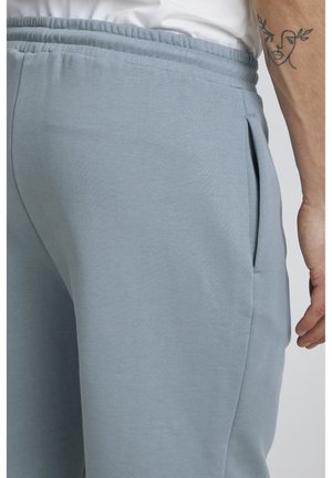 Pantalons de jogging bleu clair en tissu doux, dotés d'une taille élastique, de poches latérales et d'une texture subtile.