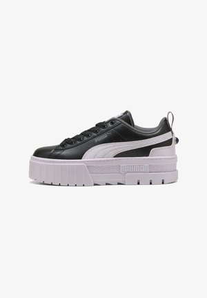 Schwarzer und weißer Sneaker mit einer dicken, strukturierten Sohle, der ein glattes Obermaterial aus Leder, eine runde Zehenpartie und ein geprägtes Logo an der Seite aufweist.