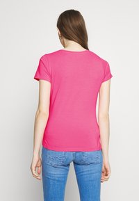 Fitted, short-sleeve t-shirt in bright pink, made from soft cotton, with a crew neckline and smooth texture. Worn with light blue jeans.