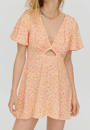 Kurzes florales Kleid aus hellorangefarbenem Stoff mit pinken Mustern, mit tiefem V-Ausschnitt und Ausschnitt-Detail an der Vorderseite. Glockenärmel.