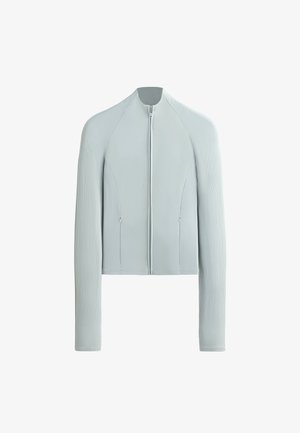 Lysegrå langærmet jakke med ribbet tekstur på ærmerne og siderne, forreste lynlås og lynlåslommer.