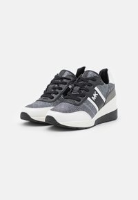 Sneakers sportive con tomaia in tessuto nero e grigio a trama, accenti sintetici bianchi, lacci piatti e suola nera rialzata per un'altezza aggiuntiva.