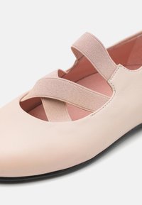 Ballerina in pelle rosa chiaro con cinturini elastici incrociati, design con ritagli aperti e superficie testurizzata. Suola nera con interni rosa chiaro morbidi.