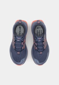 Marineblauwe sportschoenen met oranje accenten, bovenwerk van mesh, gevoerde zolen en platte veters. Beschikt over een logo en gestructureerde panelen aan de zijkanten.