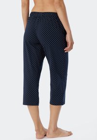 Mörkblå capri byxor med polka dots, elastisk midja, lös passform och kort längd, tillverkade av mjukt material.